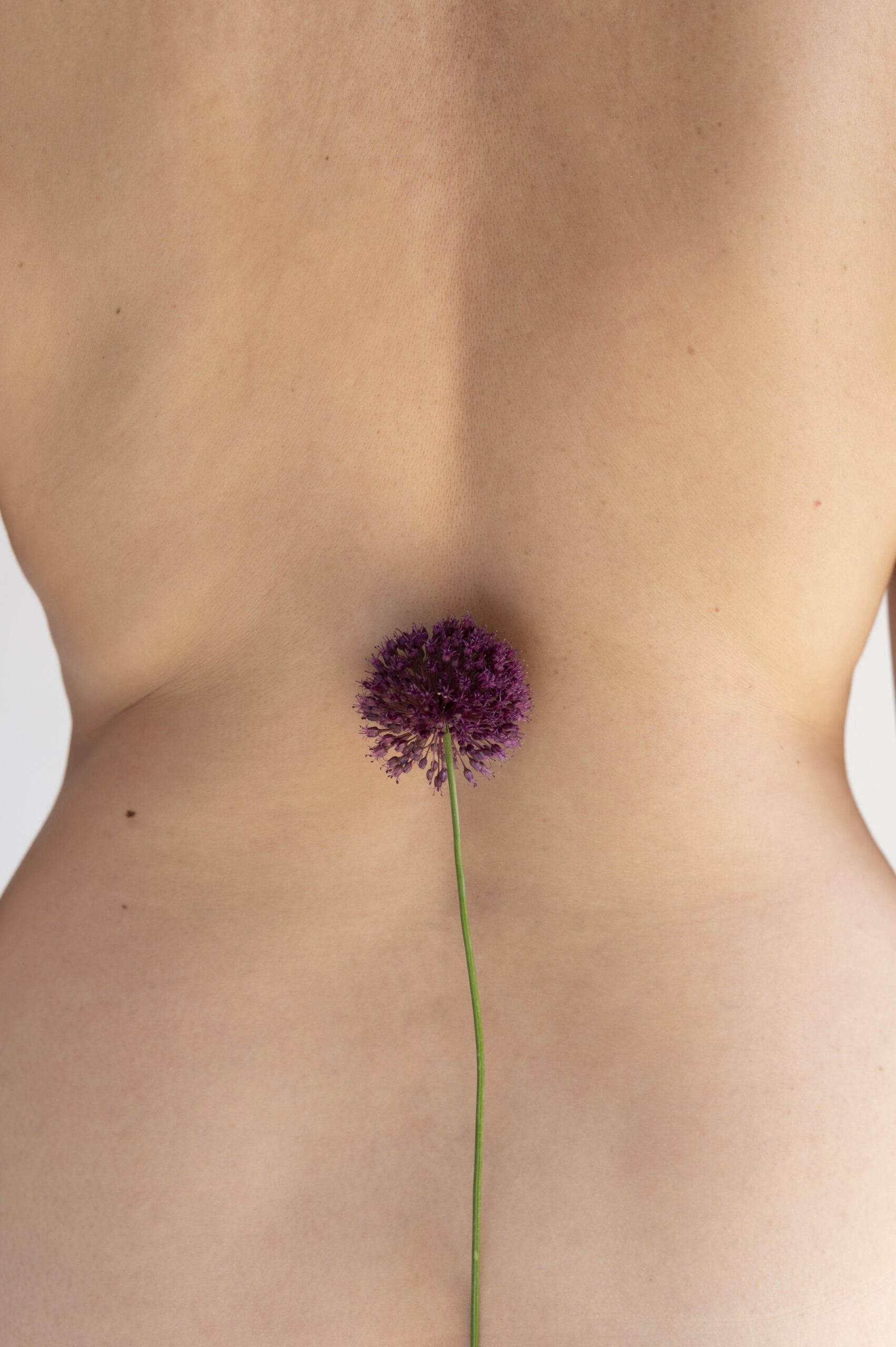 woman posing confidently nude showing back with flower